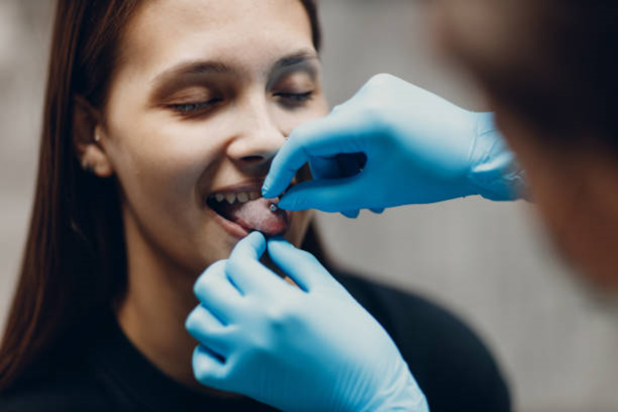 a  woman is doing tongue piercing - Gthic.com