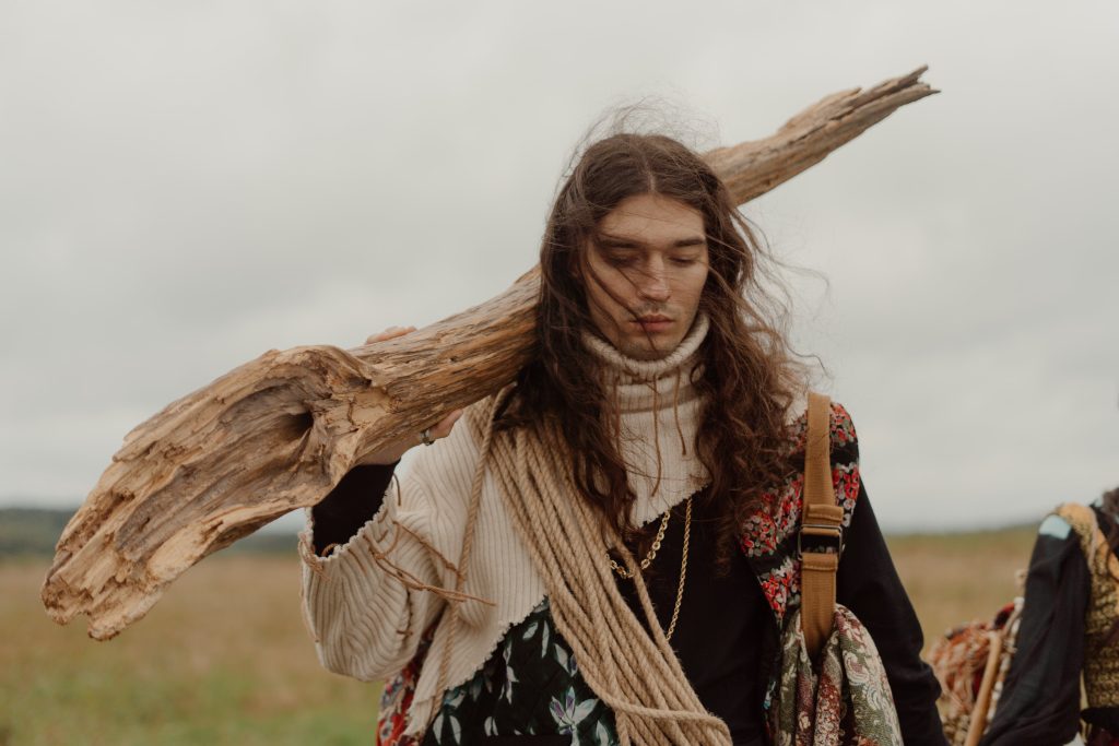 man-in-white-and-black-long-sleeve-shirt-holding-brown-wooden-stick