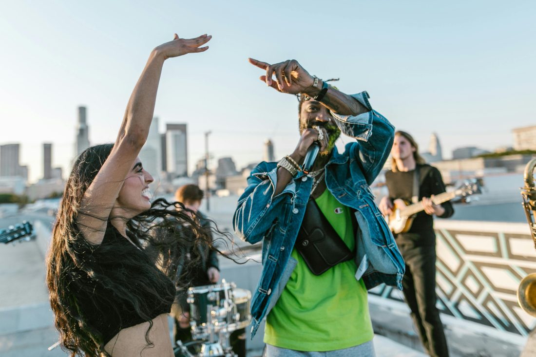 man-in-green-t-shirt-singing-beside-smiling-woman-with-raised-hand