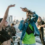 man-in-green-t-shirt-singing-beside-smiling-woman-with-raised-hand