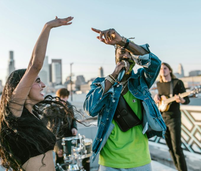 man-in-green-t-shirt-singing-beside-smiling-woman-with-raised-hand